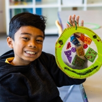 smiling kids holds up completed Art Lab project